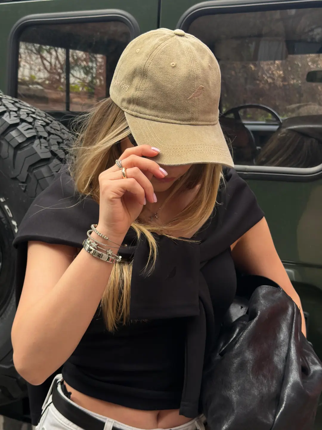 Trace Cap Moss ve siyah Quiet Tee, bir arazi aracının önünde